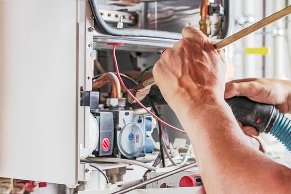 Técnico instalando calentador de gas con herramientas de fontanería