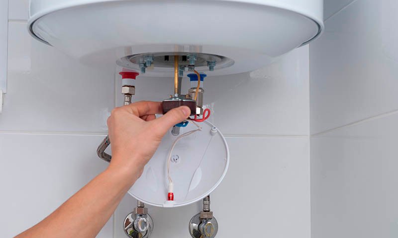 Técnico realizando instalación y ajuste de termo eléctrico doméstico